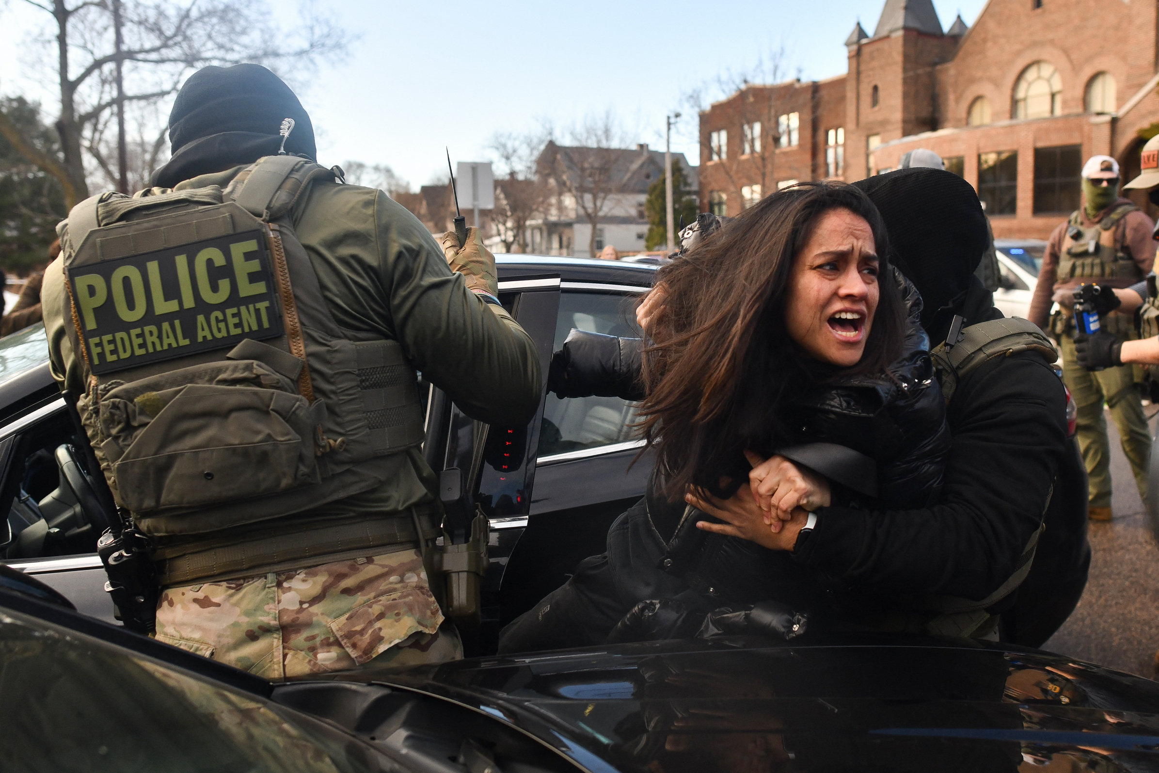 Des agents de la police de l’immigration (ICE) et d’autres forces fédérales font sortir une femme de son véhicule près d’une zone d’intervention de l’ICE
